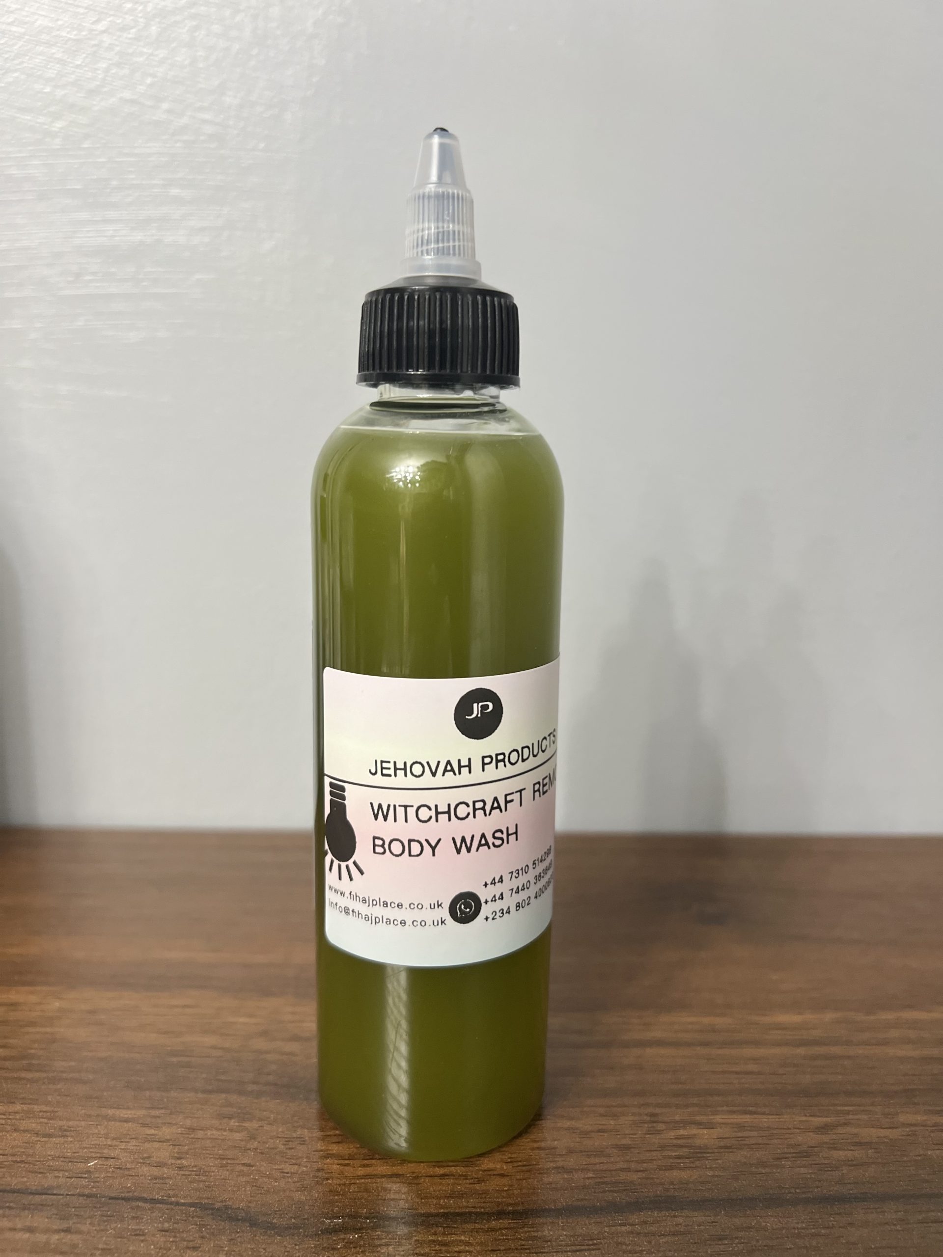 “Bottle of green Jehovah Products Witchcraft Removal Body Wash on a wooden surface.”