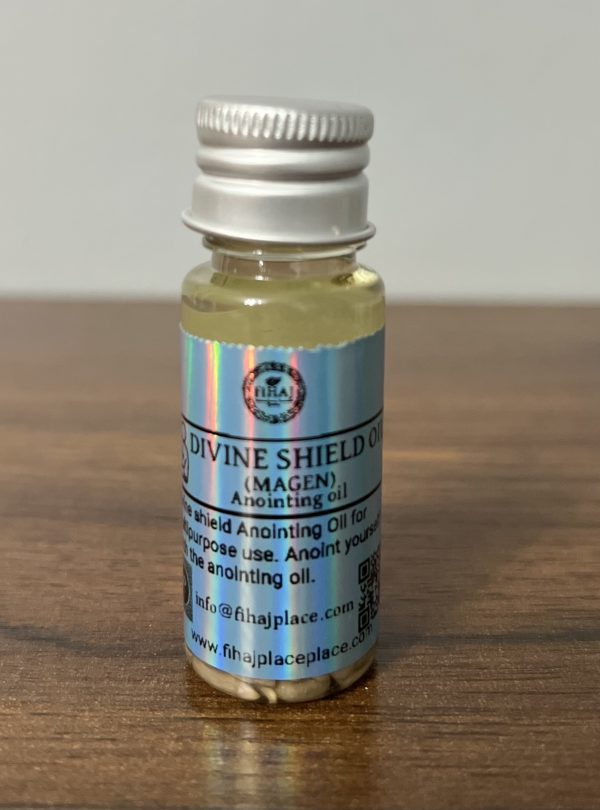 Small bottle of Divine Shield Oil (Magen) anointing oil with holographic label on wooden surface.”