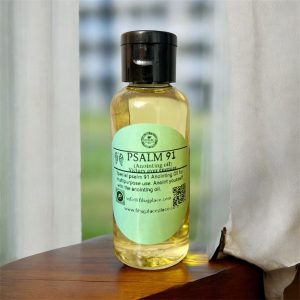 “Bottle of Psalm 91 anointing oil with green label on a wooden surface beside a white curtain.”