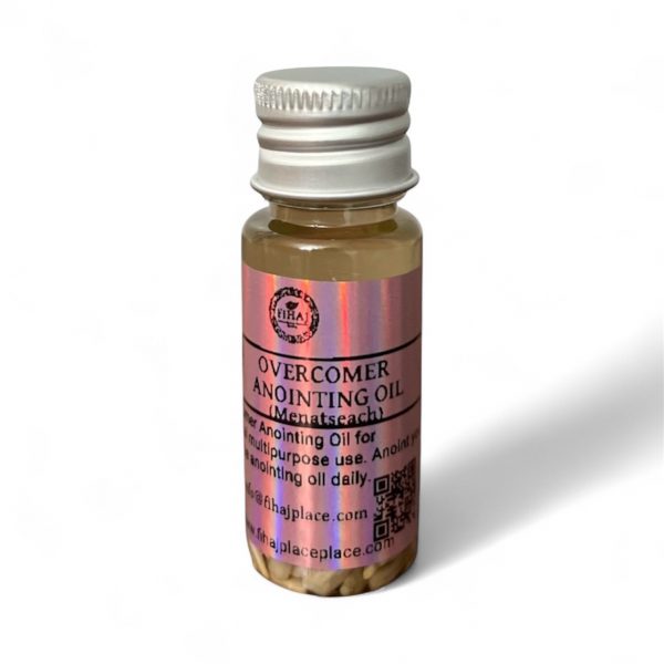 Bottle of Overcomer Anointing Oil with pink label and silver cap containing small herbal pieces at the bottom.