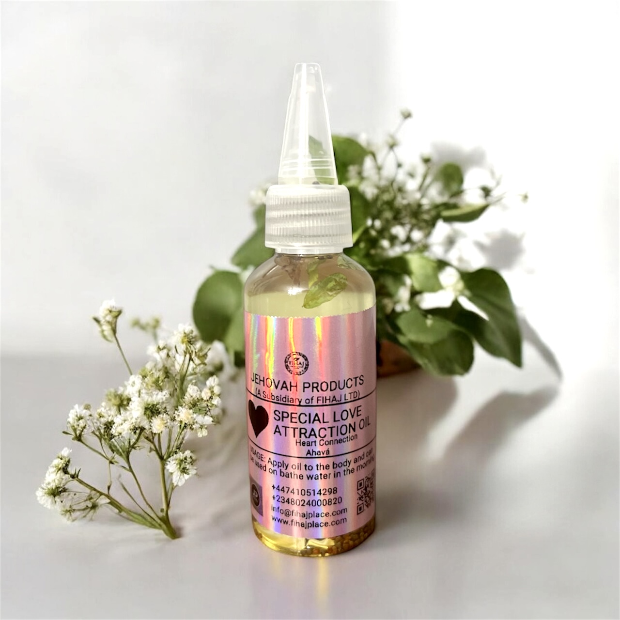 “Bottle of Jehovah Products Special Love Attraction Oil displayed with white flowers and green leaves on a light background.”